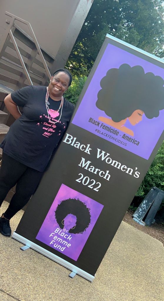 Participant at Black Women's March 2022 standing next to sign at the march
